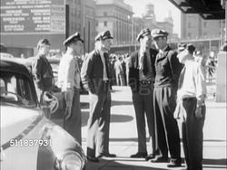 1950: DENVER, COLORADO: STREET SCENE: Men in work uniform w/ cap, possibly cabbie or porter, standing on sidewalk w/ taxi car fender FG. Corner WS The Boston Building w/ people walking FG. Instructional Video