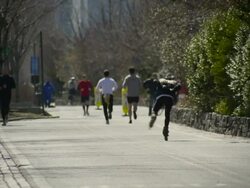 People bike and run down a bike lane in the Hudson river park on the west side an inline skater travels by Stock Footage