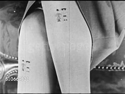 1920s: FASHION: STOCKING ART: MS Sitting woman's exposed legs w/ skirt resting on top of knees exposing embroidered leg art on stockings: caricatures of Laurel & Hardy, second woman w/ soldiers in European uniform.   Cotton, wool, silk, rayon, fad. Instructional Video