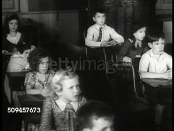 1901-1919: U.S. EARLY ONE ROOM SCHOOL: DRAMATIZATION: MS Children in class reciting (no SOT). CU Blackboard w/ historical dates. MS Children. CU Opened book 'Geography.' MS Teacher w/ ruler pointing to US map, reciting (SOT). Turn of century Instructional Video