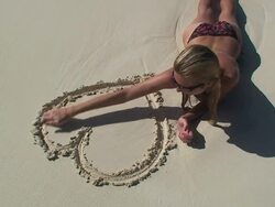 Woman on the beach drawing a heart deleted by sea Stock Footage