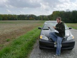 MS Man sitting on hood of parked car at rural road and reading road map / Illinois, United States Stock Footage