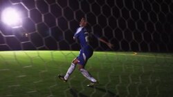 Wideshot from behind net; male soccer player receives pass &amp; kicks ball past goalie to score Stock Footage