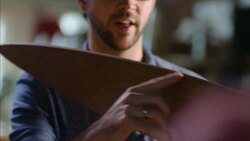 Young craftsman answers questions and shows off elegant wooden longboard design Stock Footage