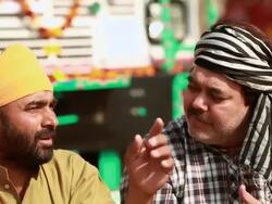 Two truck drivers drinking tea at a tea stall and talking, Ballabgarh, Haryana, India Stock Footage