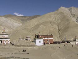 WS PAN View of Traditional himalayan house and villagers threshing barley in spectacular mountains / Saldang village, High Himalayas, Upper Dolpo near Tibetan border, Nepal   Stock Footage