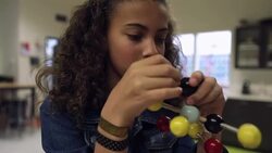 Close up of schoolgirl examining atom model Stock Footage