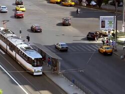 MS TU Cars and tram flowing on busy street in front of building / Bucharest, Romania Stock Footage
