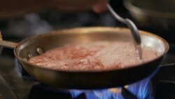 Chef stirs boiling scallops in skillet over flaming stove top in restaurant kitchen Stock Footage