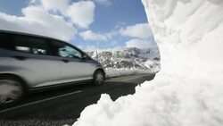 traffic passing large snowdrifts on the A591 road at Thirlmere in the Lake District, UK, following the unseasonal extreme weather events of late march 2013. Stock Footage