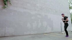 Cool young woman practicing martial arts spinning kick in urban parking lot Stock Footage