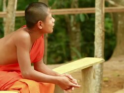 MS SLO MO Shot of novice monk sitting on bench and smiling / Mountain village near Muang Ngoi, Luang Prabang, Laos Stock Footage