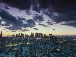 WS T/L View of sunset over shinjuku business and shopping area with dark clouds moving in sky / Tokyo, Japan Stock Footage