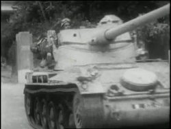 A tank with the words Nasser's Nightmare rolls through an Egyptian street as buildings burn. News Clip