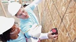 Diverse volunteers measure plywood on home being built for charity Stock Footage