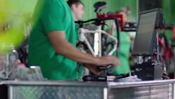 Bike shop cashier scans product barcode for customer at sales counter Stock Footage