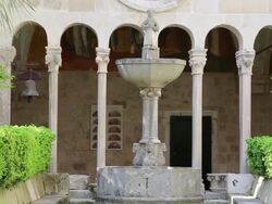 Gothic fountain with a statue of Saint Francis in the Romanesque and Gothic cloister of the Franciscan Monastery, Dubrovnik Stock Footage