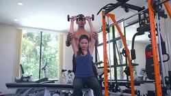 Sport girl doing weight exercises with assistance of her personal trainer at public gym Stock Footage