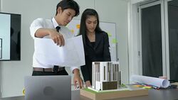 Businessman and businesswoman are working on paper blueprint and building model. Business woman suggest idea to designer. concept of construction, architecture, development and creative. Stock Footage