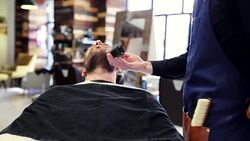 man and barber with trimmer trimming beard at shop Stock Footage