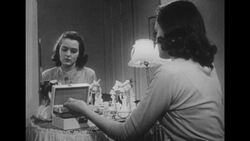 1950s: Wife walks to vanity table and sits Stock Footage
