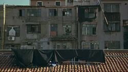 WIDE ANGLE OF LOWER CLASS MULTI-STORY APARTMENT BUILDING. MAN IN WINDOW. SPANISH TILE ROOFTOP. COULD BE CONSTRUCTION OR RENOVATION TAKING PLACE. Stock Footage