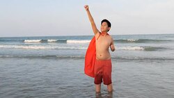 Asian preteen boy in red cover standing on the beach with superhero concept, slow motion. Stock Footage