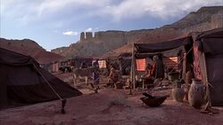 WIDE ANGLE OF SMALL DESERT CAMP. COULD BE NOMADIC PEOPLE. TENTS. FIRE PITS. DONKEY. MOUNTAINS, CLIFFS, MESAS OR PLATEAUS IN BG. ACTUALLY IN NEW MEXICO. COULD BE MONUMENT VALLEY, UTAH IN BG. Stock Footage