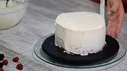 Close up of hands smearing butter cream on chocolate cake by white spatula. Stock Footage