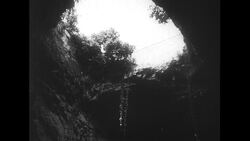 United States, c.1951: Ropes hang from a widened hole in a sparsely-populated area in Italy Stock Footage