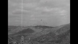 During Korean War, US soldiers in positions on hillside in South Korea watch US artillery shells exploding on nearby mountains News Clip