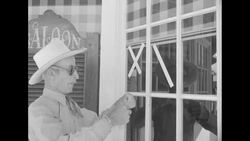 Man and woman holding baby put tape on windows at saloon and home prior to atomic test News Clip