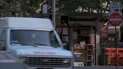 PAN RIGHT TO LEFT FROM NEWSPAPER STAND ON STREET CORNER ACROSS CITY STREET WITH CARS. GREENWICH VILLAGE, MANHATTAN. SHOPS AND STOREFRONTS. Stock Footage