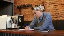Barber writing a receipt at checkout counter Stock Footage