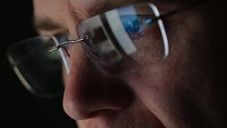 REFLECTION: Close Up of face of adult man in an eyeglasses looking a website Stock Footage