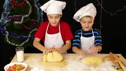 Two kids kneading the dough for christmas cookies together Stock Footage