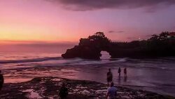 Beautiful sea with Pura Batu Bolong temple on rock cliff at sunset Stock Footage