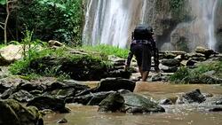 Adventurers Senior man. walking through small stream river of  waterfall in the forest. Adventures and extreme tourism, overcoming obstacles. Travel Lifestyle and success concept. Video Slow motion Stock Footage