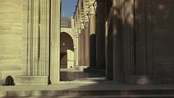 WIDE ANGLE OF INTERIOR STONE COURTYARD. PILLARS OR COLUMNS. STRIPED POINTED ARCHES. ISLAMIC ARCHITECTURE. SULEYMANIYE MOSQUE. DOME VISIBLE IN BG. POV THROUGH ENTRANCE. Stock Footage