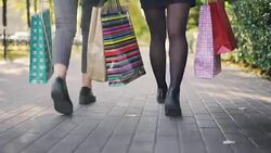 Low angle shot of women's legs walking in the street with colorful paper bags after busy day in shops. Young people, shopping and friendship conccept. Stock Footage