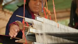 Traditional textile manufacture in craft village where old women work on wooden weaving loom machines and spin yarn creating silk or cotton fabric. Silk weaving in Thailand. Stock Footage