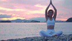 Happy young woman relaxing by practicing yoga on the beach at sunset, Sunrise background. Fitness, sport, yoga and healthy lifestyle concept. Stock Footage