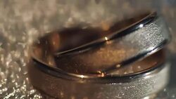 Wedding rings lying on shiny surface shining with light close up macro Stock Footage