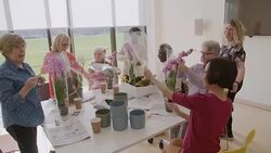 Instructor helping active senior students learning to arrange orchid flowers Stock Footage