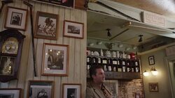 Waiter walking by wall covered in photos and a pendulum clock Stock Footage