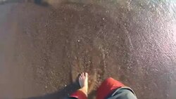 Feet with wave on sandy beach top view slow motion Stock Footage