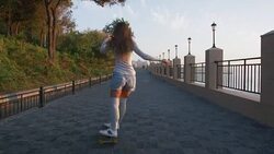 Young stylish attractive woman skateboarding at sunrise on seafront, slow motion Stock Footage