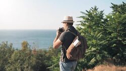 Happy male tourist with backpack. Man making pictures with a retro camera while traveling . Stock Footage