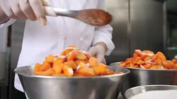 hands pastry chef spread the sugar on the apricots fruit, prepare the jam in industrial kitchen worktop Stock Footage