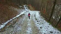 man with backpack hiking the mountain on a winter day, back flying camera Stock Footage